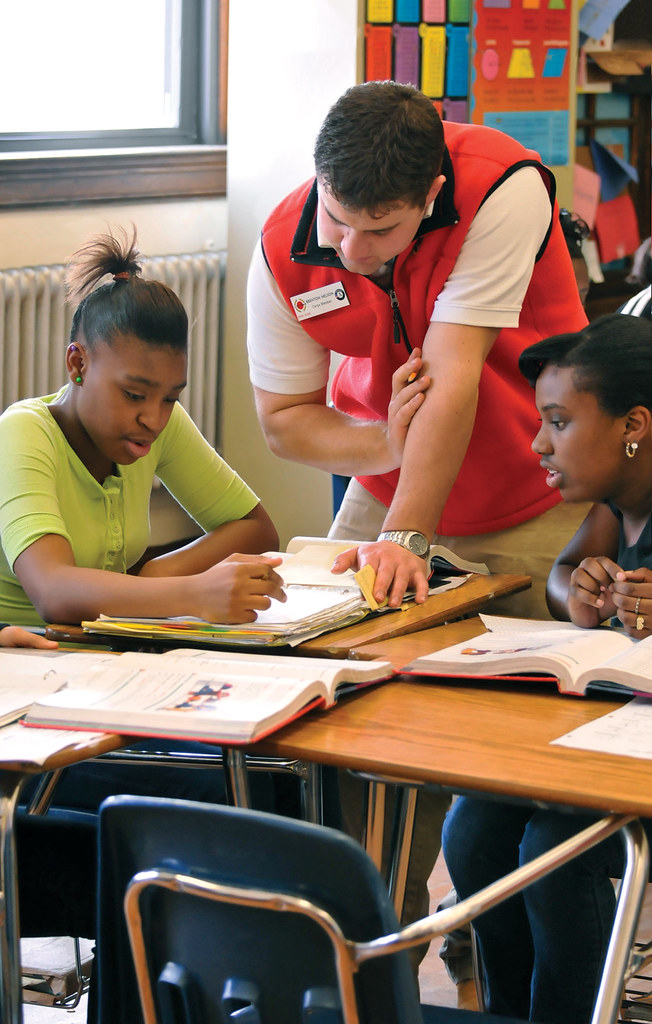 A male teacher tutors two female students.